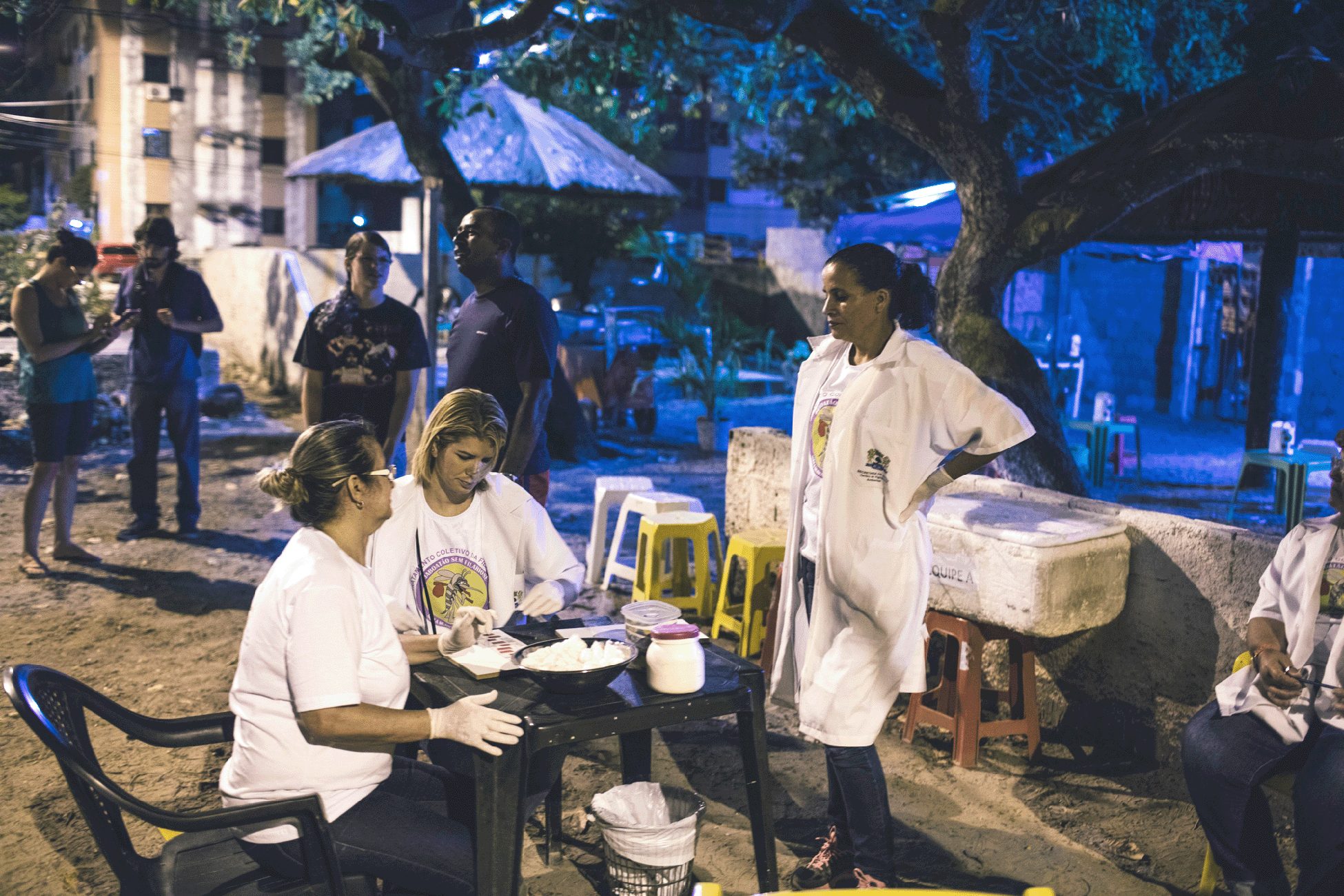 Health-care workers sitting at and standing round a table in an outdoor setting
